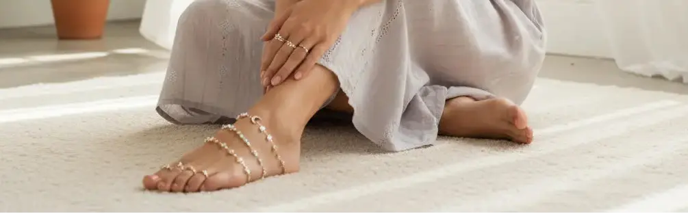 Woman sitting on a light-colored floor in a bright room with white curtains and a plant.