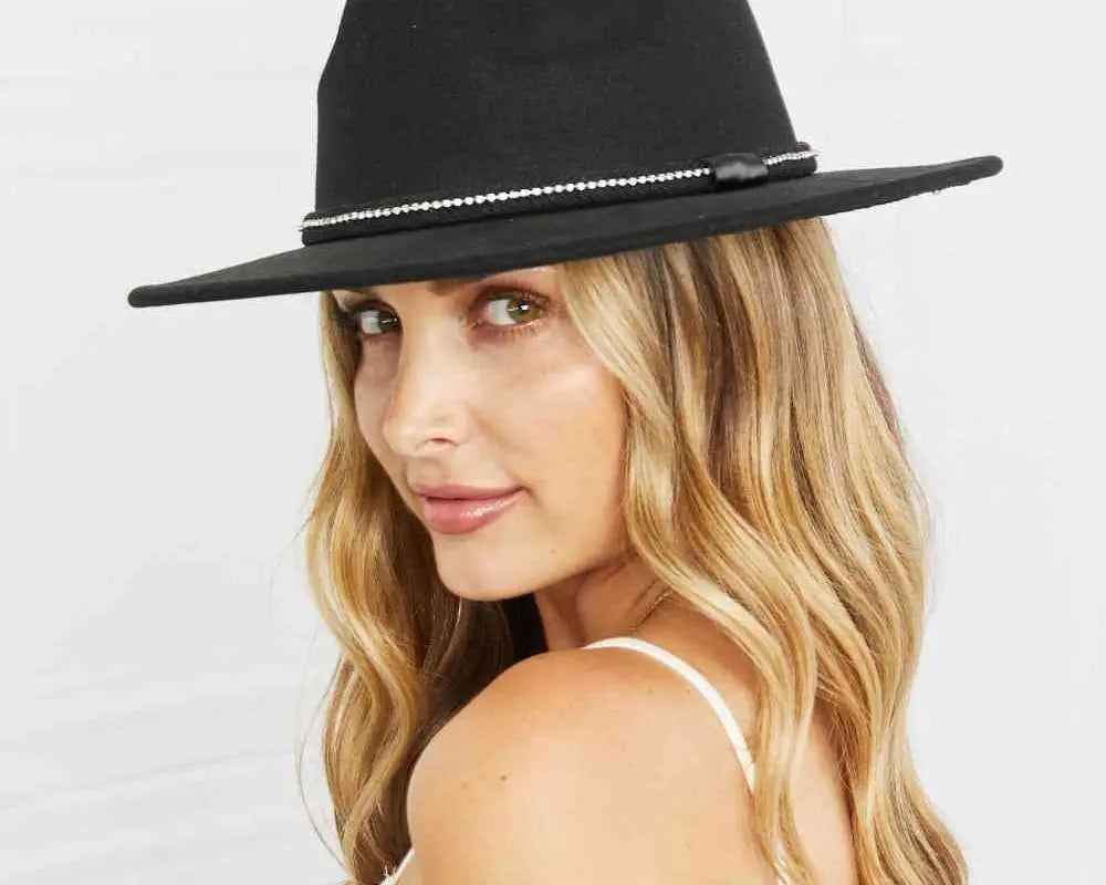 Woman wearing a black fedora hat against a white background.