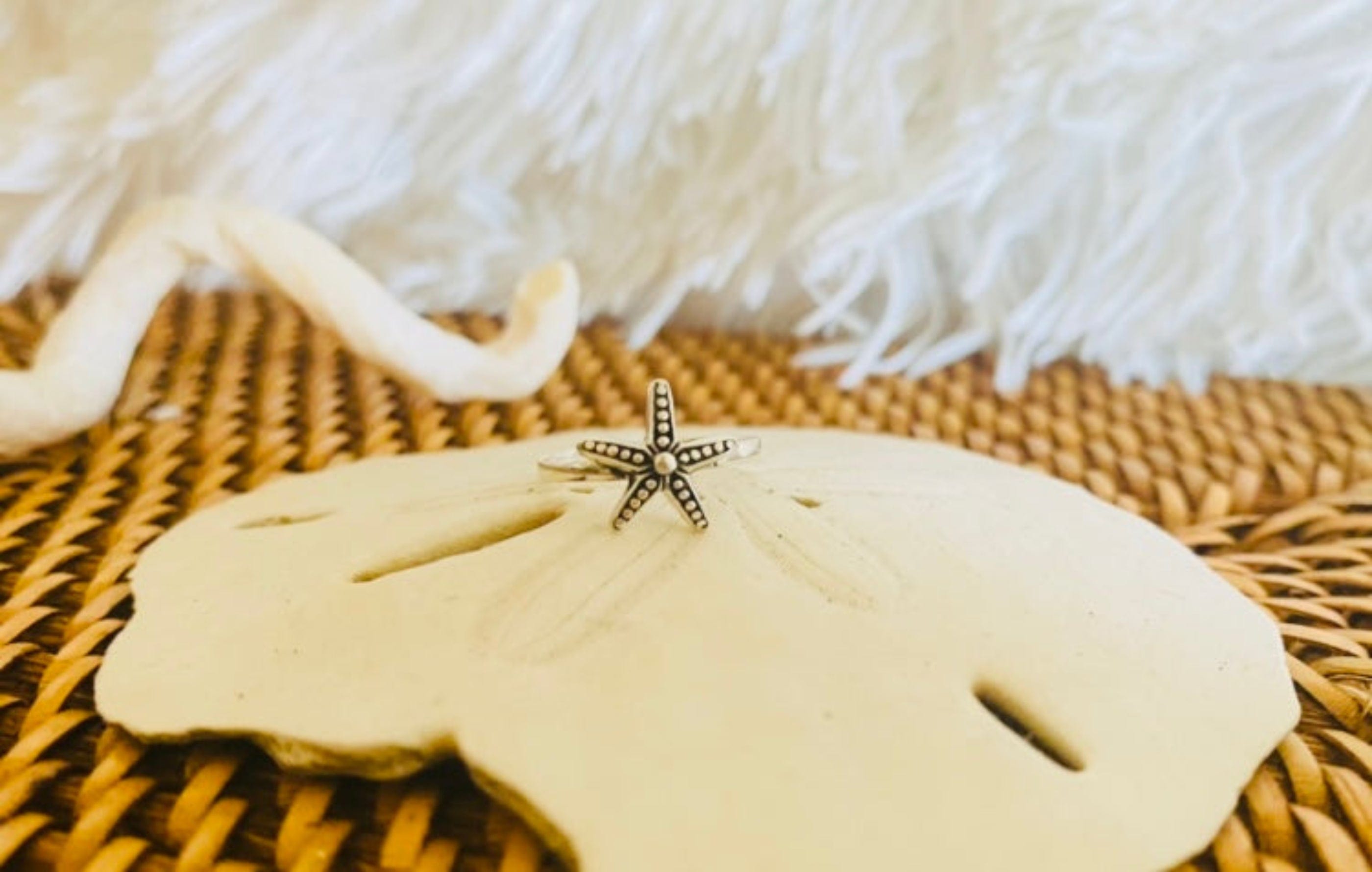 Beautiful starfish toe ring resting on a sand dollar, symbolizing coastal style and summer vacations.