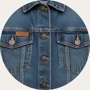Close-up of a blue denim jacket with buttons on a white background.