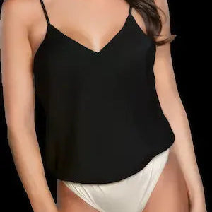 Woman wearing a black camisole and white underwear against a black background.
