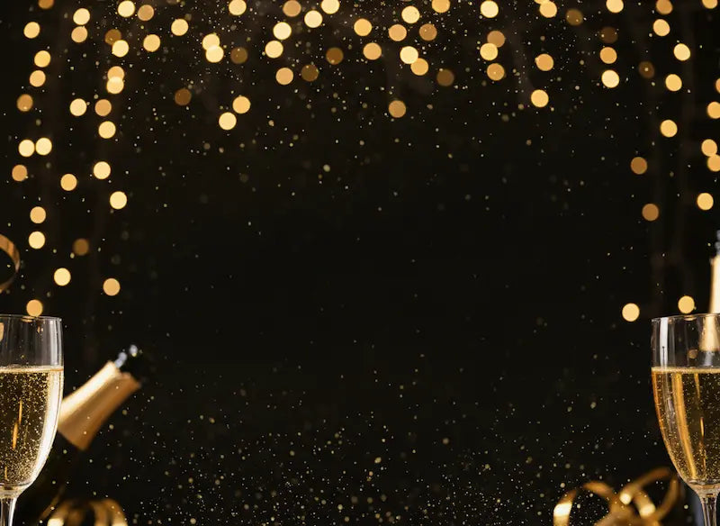 Two glasses of champagne with a bottle against a black background with gold confetti.