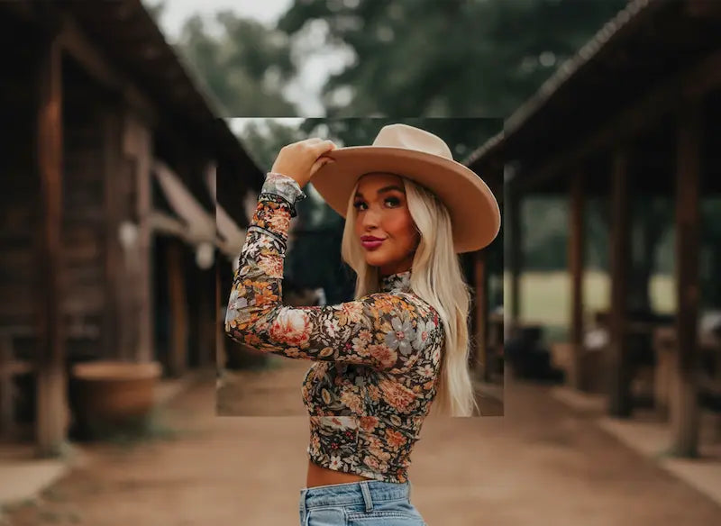 Woman wearing a floral top and cowboy hat in a rustic setting.