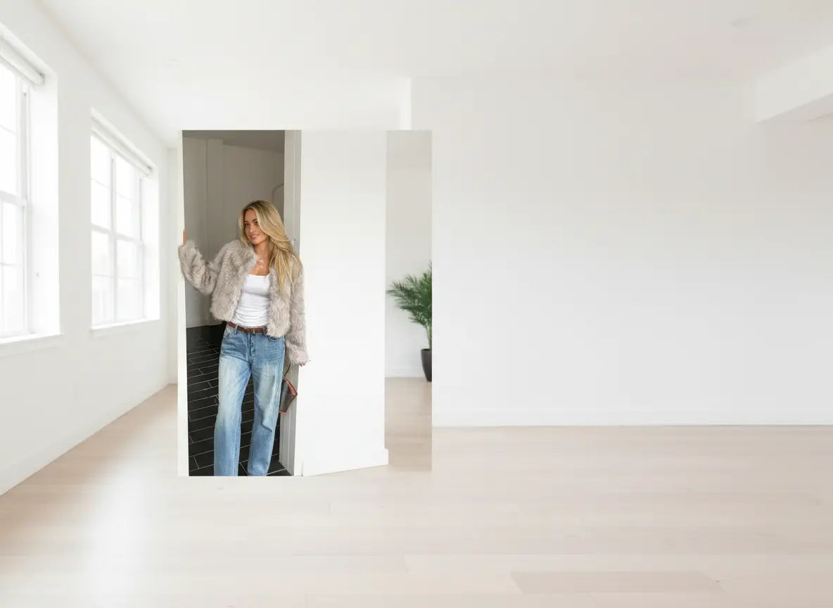 Woman standing in a minimalistic room with large mirrors.