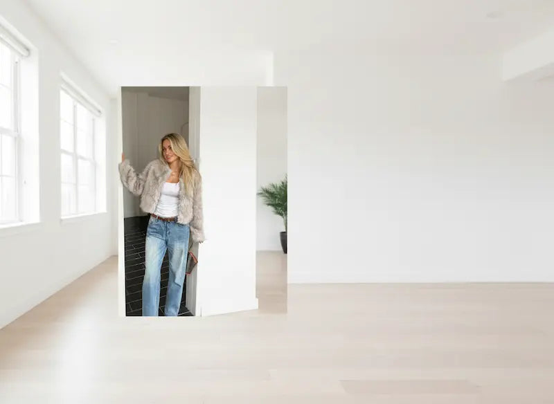 Woman standing in a minimalistic room with large mirrors on the wall.