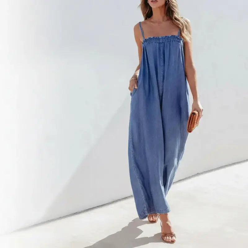 Woman wearing a blue denim jumpsuit against a white background.