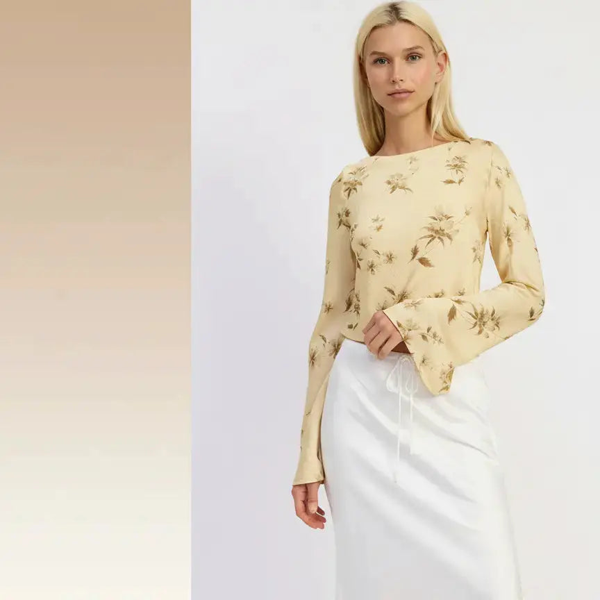 Woman wearing a beige floral blouse and white pants on a white background