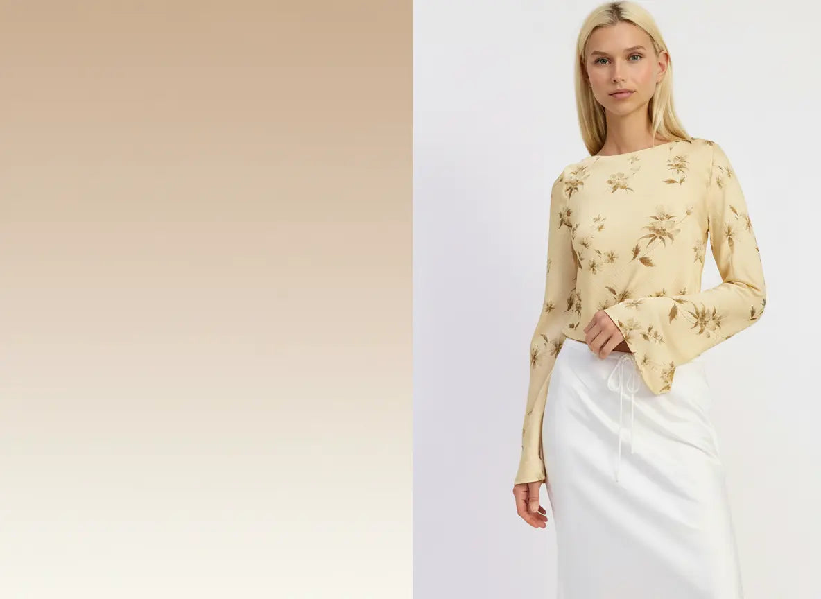 Woman wearing a yellow floral blouse and white skirt against a light background.