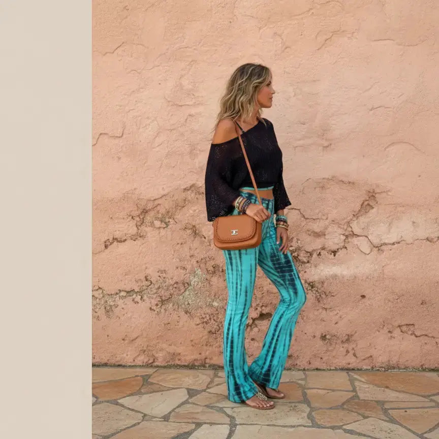 Woman wearing a black top and blue striped pants against a textured pink wall.
