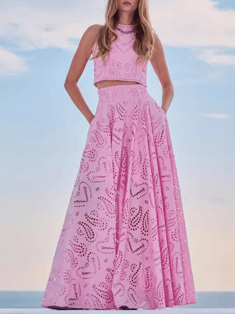 Woman elegantly posing in a trendy matching pink crop top and long maxi skirt, showcasing the stylish options across all of our collections.
