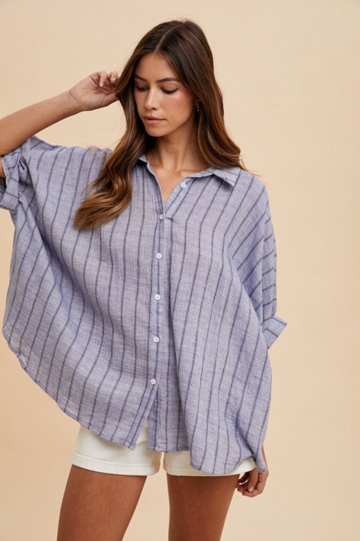 Model playfully posing in an oversized light blue striped button-down top, showcasing the laid-back styles from our Casual Tops collection